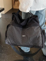 Person holding a black and gray checkered bag with 'DEAM' branding.