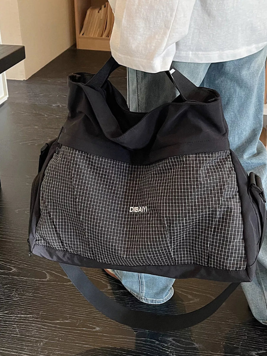 Person holding a black and gray checkered bag with 'DEAM' branding.