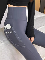 A close-up of a person wearing high-waisted slate gray leggings with a side pocket holding a white smartphone. The leggings have a white dashed line graphic and the brand name 'myos' printed on the pocket.
