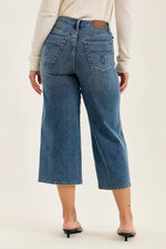 Person wearing blue jeans on a plain background