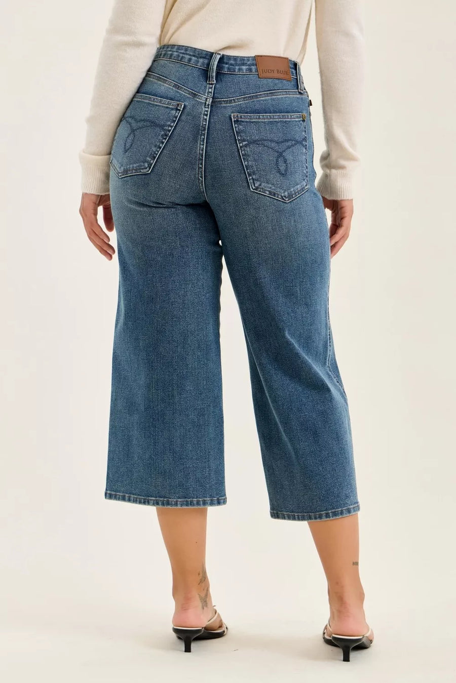 Person wearing blue jeans on a plain background