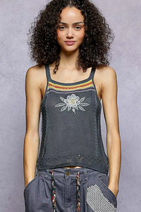 Woman wearing a tank top with a floral design against a gray background