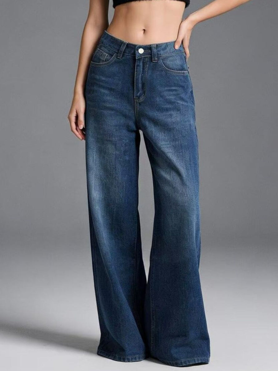Person wearing blue wide-leg jeans on a gray background
