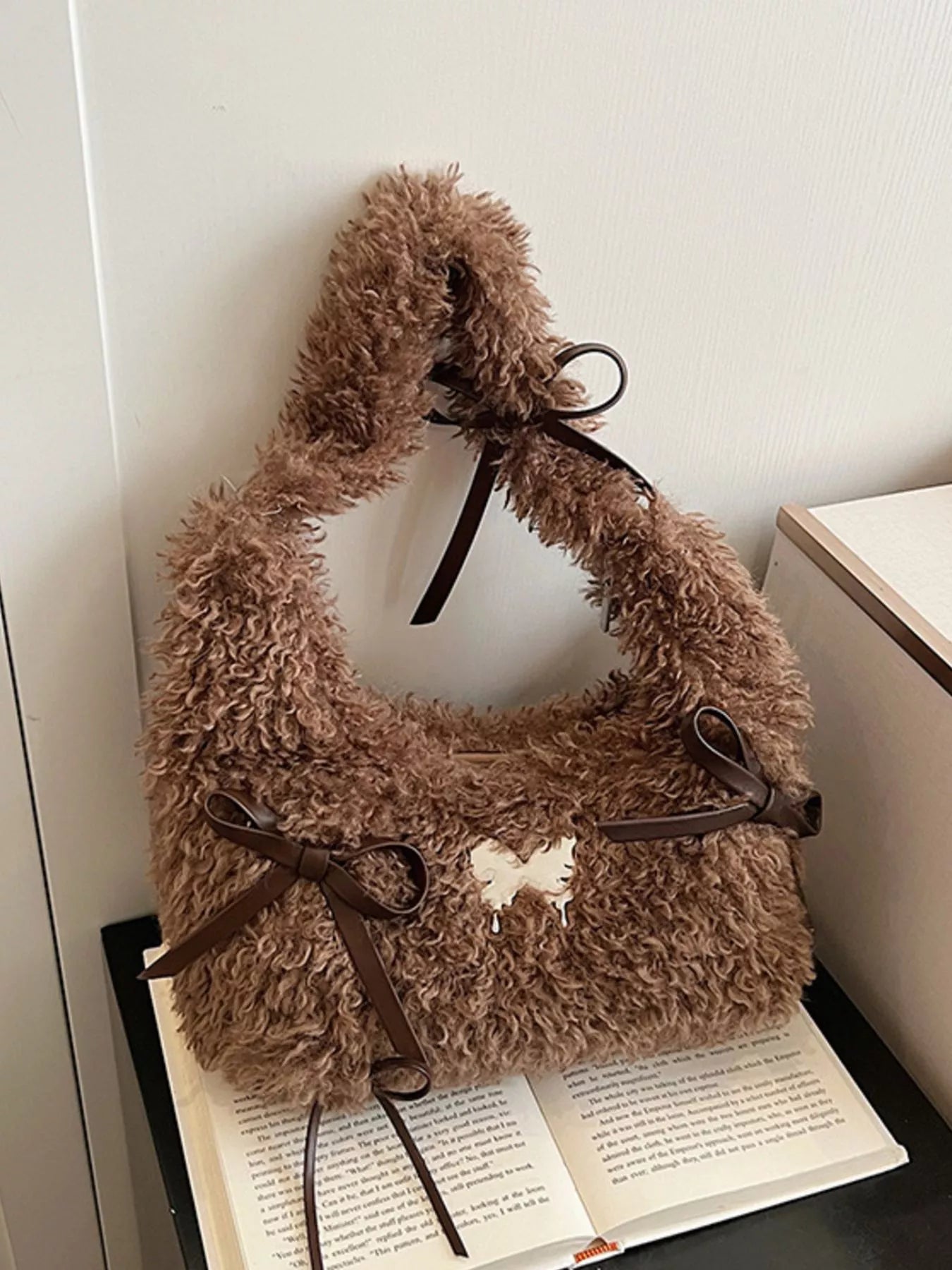 Brown fluffy handbag with a bow on a white surface