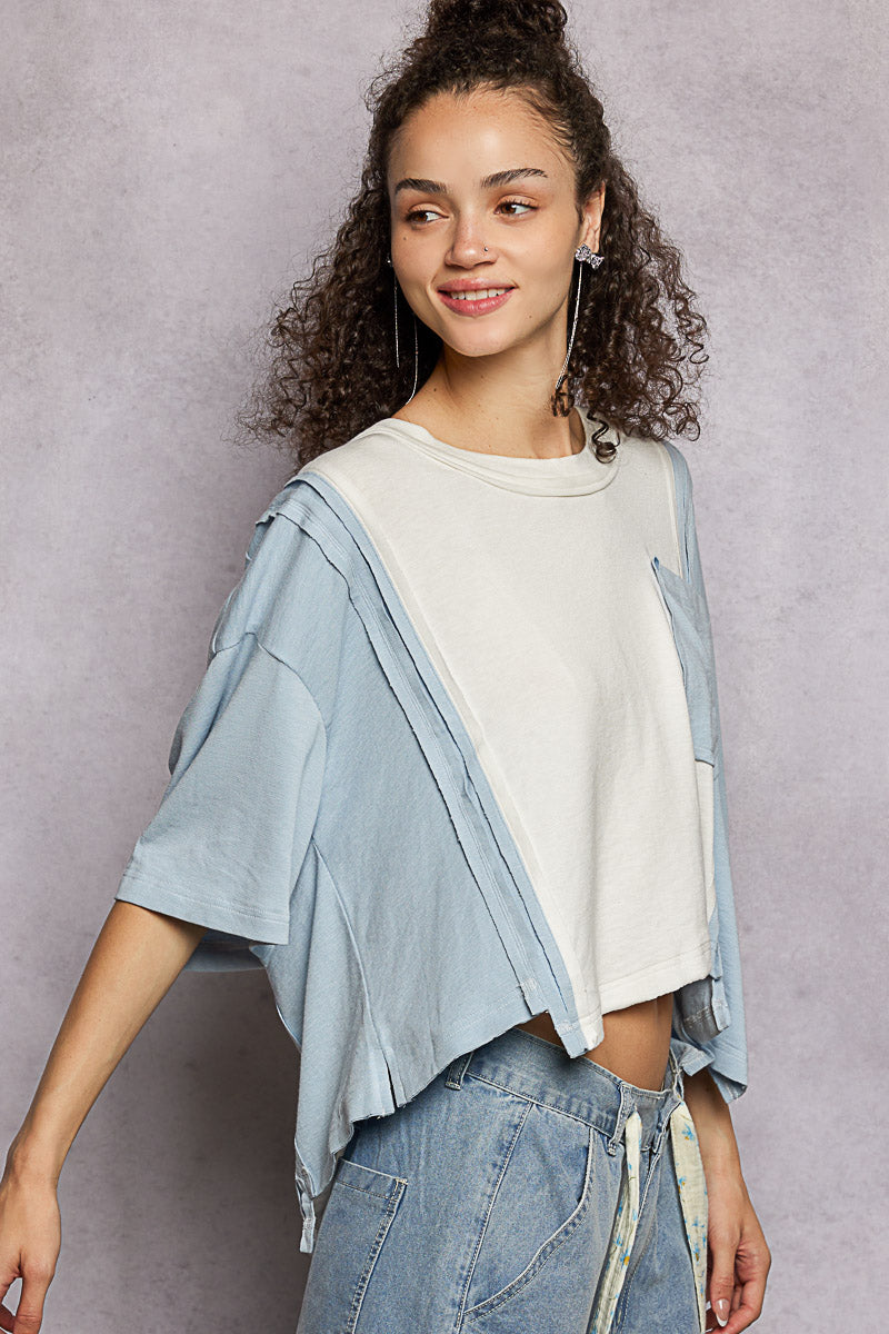 Woman wearing a light blue jacket over a white shirt with jeans against a gray background