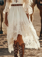 Person wearing a white lace dress with brown boots standing in a desert-like setting.