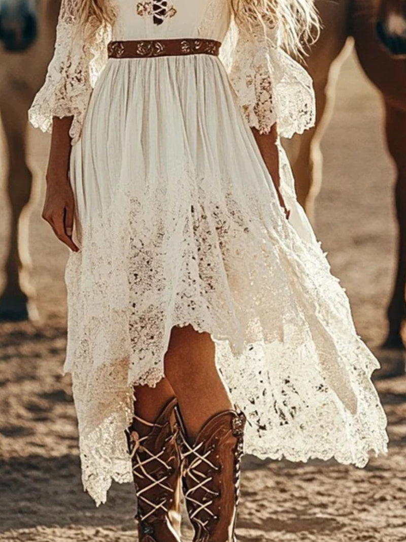Person wearing a white lace dress with brown boots standing in a desert-like setting.
