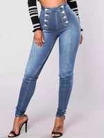Blue jeans with decorative buttons worn by a person on a light gray background