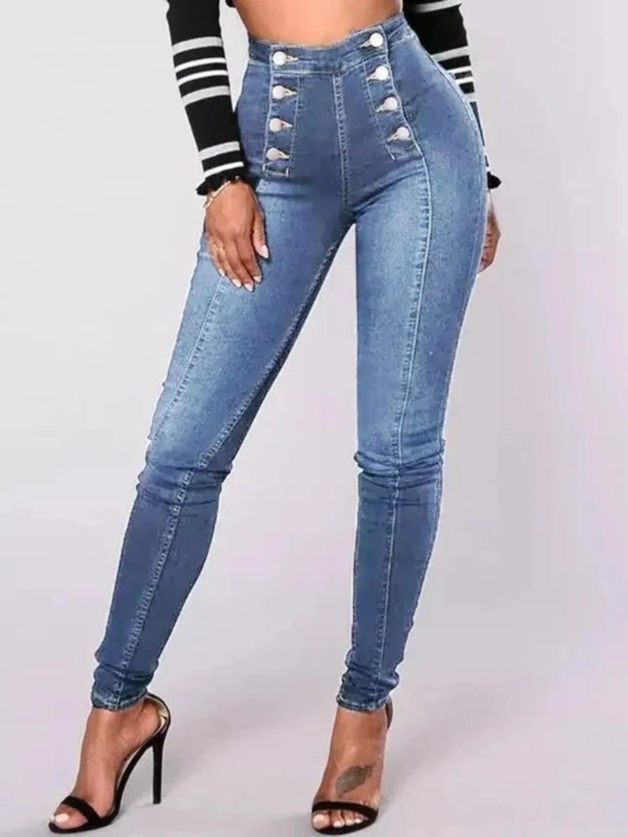 Blue jeans with decorative buttons worn by a person on a light gray background