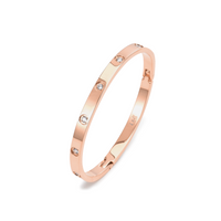 A rose gold bangle bracelet with eight stone embellishments, featuring a polished finish.