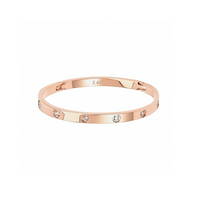 A rose gold bangle bracelet with eight stone embellishments, featuring a polished finish.