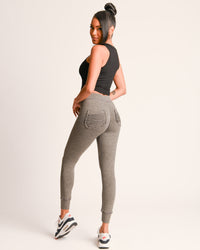 Woman wearing gray jogger pants on a white background