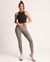 Woman wearing a black crop top and gray leggings on a white background