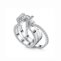 A set of two silver-colored rings, one with a prominent central diamond-like stone and surrounded by smaller stones, and a second eternity band with similar stones around its entire circumference.