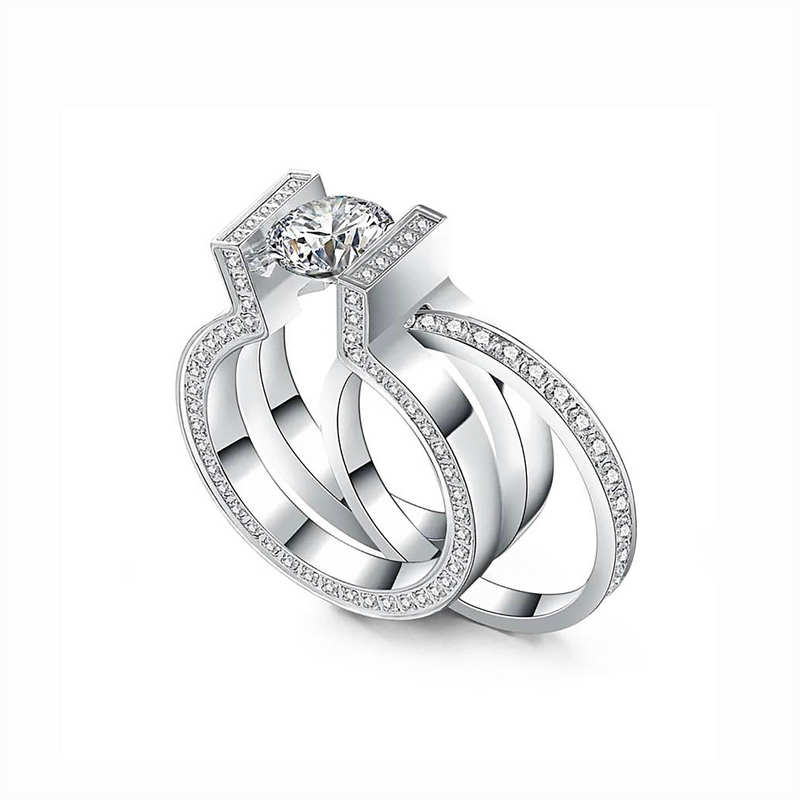 A set of two silver-colored rings, one with a prominent central diamond-like stone and surrounded by smaller stones, and a second eternity band with similar stones around its entire circumference.