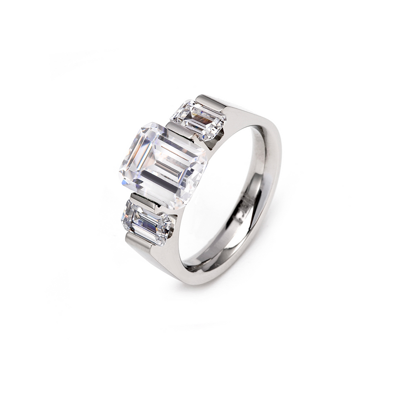 An emerald cut engagement ring with a central stone and two side stones set in a silver-colored band