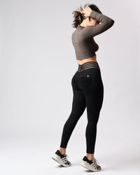Woman wearing a brown crop top and black leggings on a light gray background
