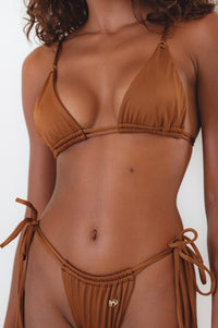 A close-up of a red bikini top with tie details and a triangle cup design, accompanied by matching bottoms, although the bottom is not in the frame.