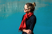 Woman wearing a red scarf and sunglasses against a blue background