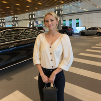 Woman standing in a modern indoor setting with cars in the background