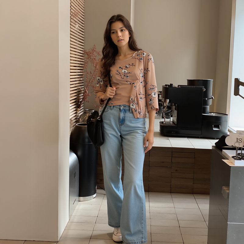 Woman in a floral top and jeans standing in a kitchen.