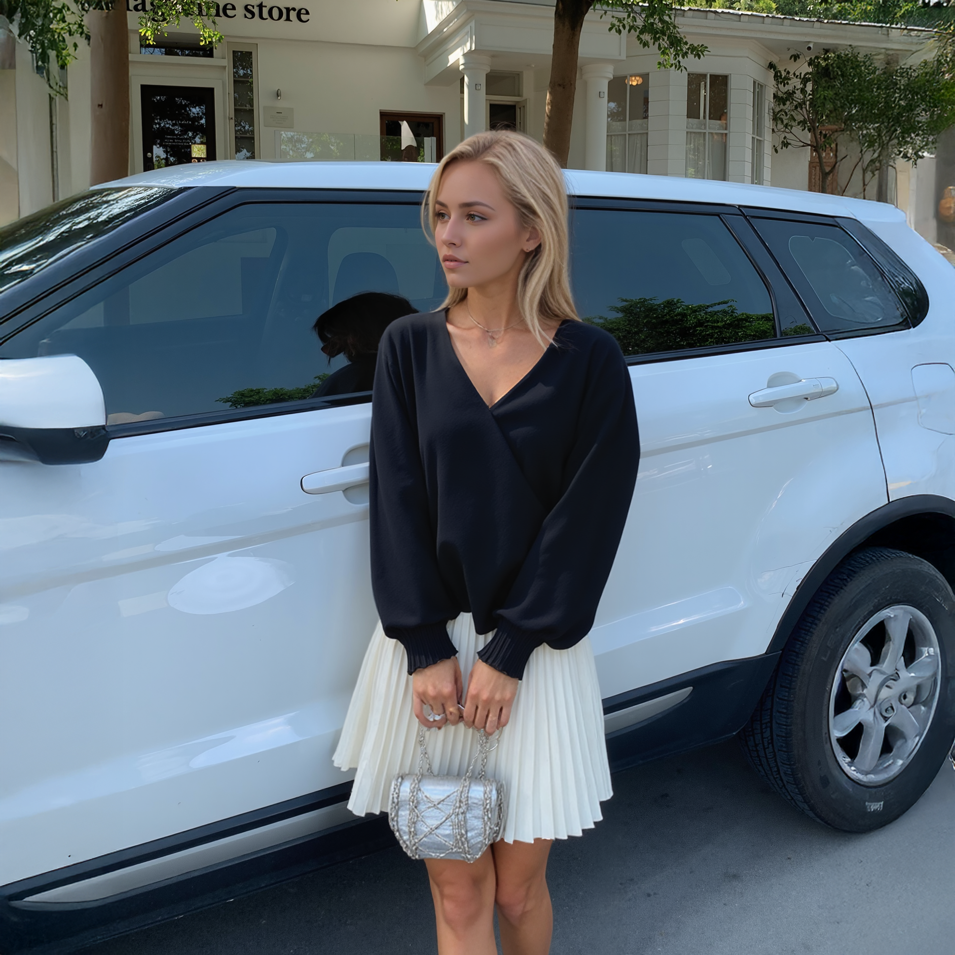 Woman in black top and white skirt standing next to a white car