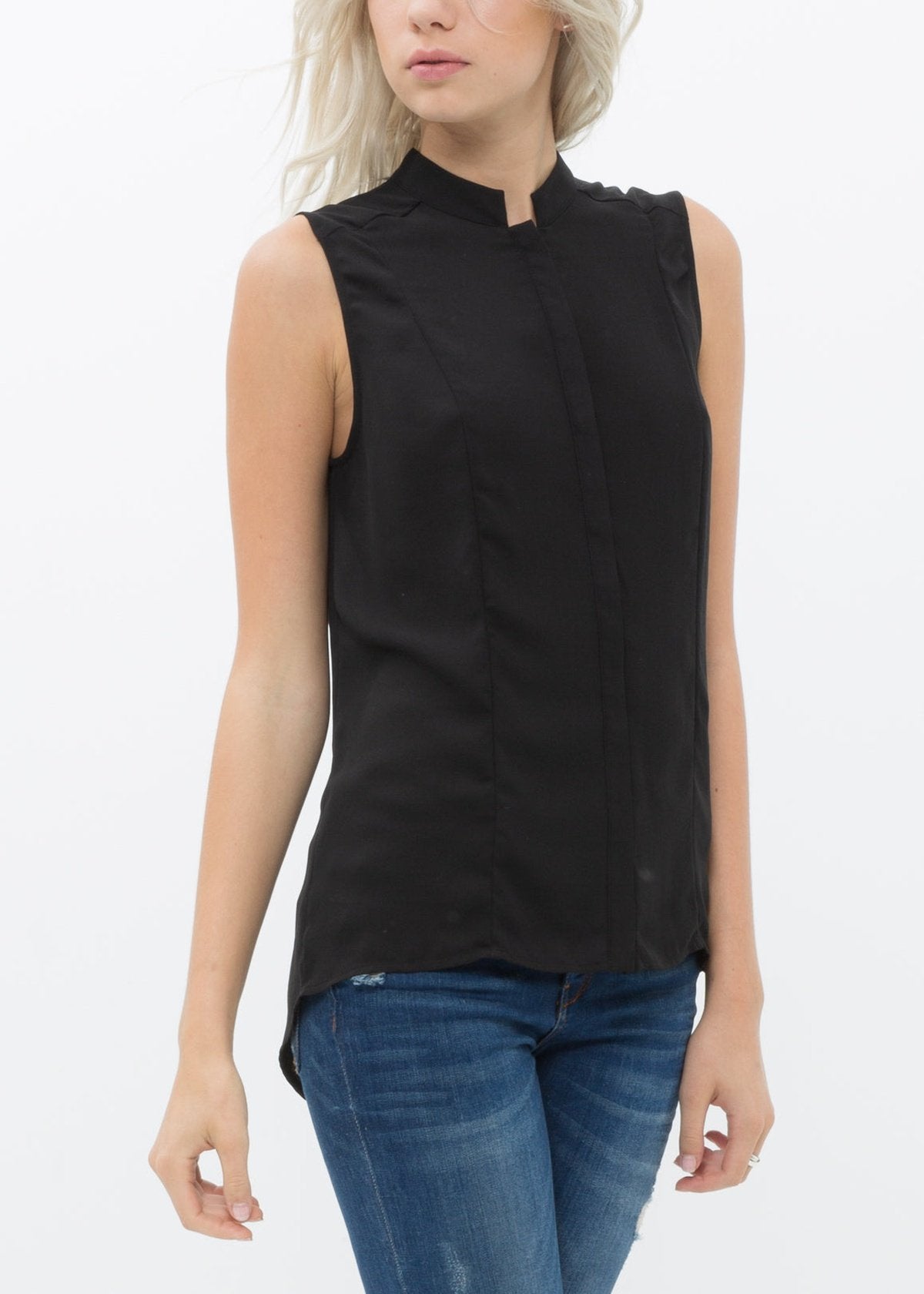 A woman wearing a black sleeveless blouse with a stand collar and hidden-button fly closure. The blouse has a hi-lo slit hem.
