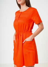 A woman showing the pockets on Women's Short Sleeve Utility Dress in Poppy