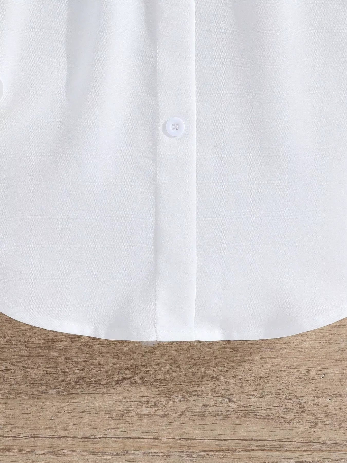 Close-up of a white shirt collar on a wooden surface