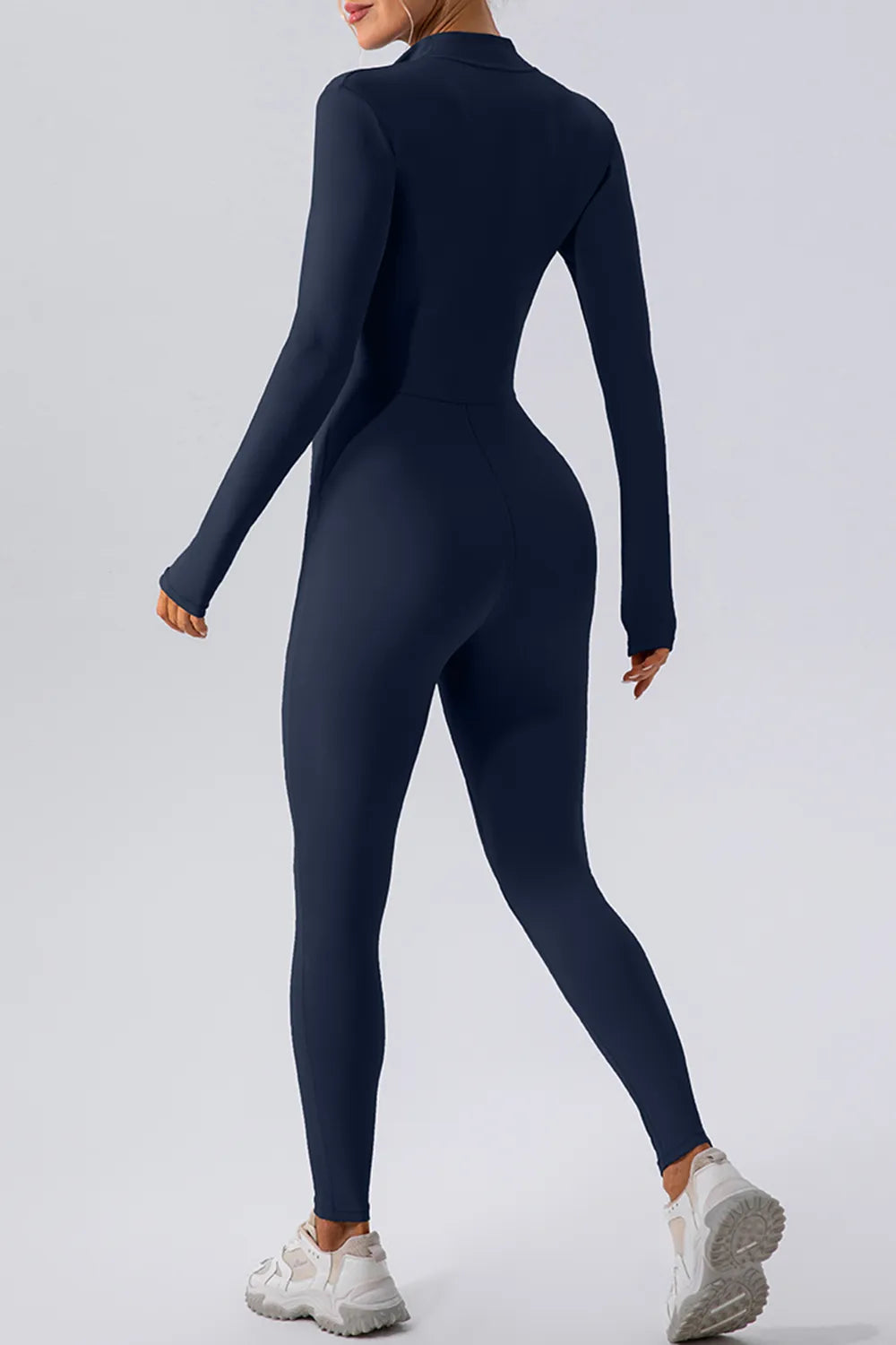 Person wearing a navy blue jumpsuit on a light gray background
