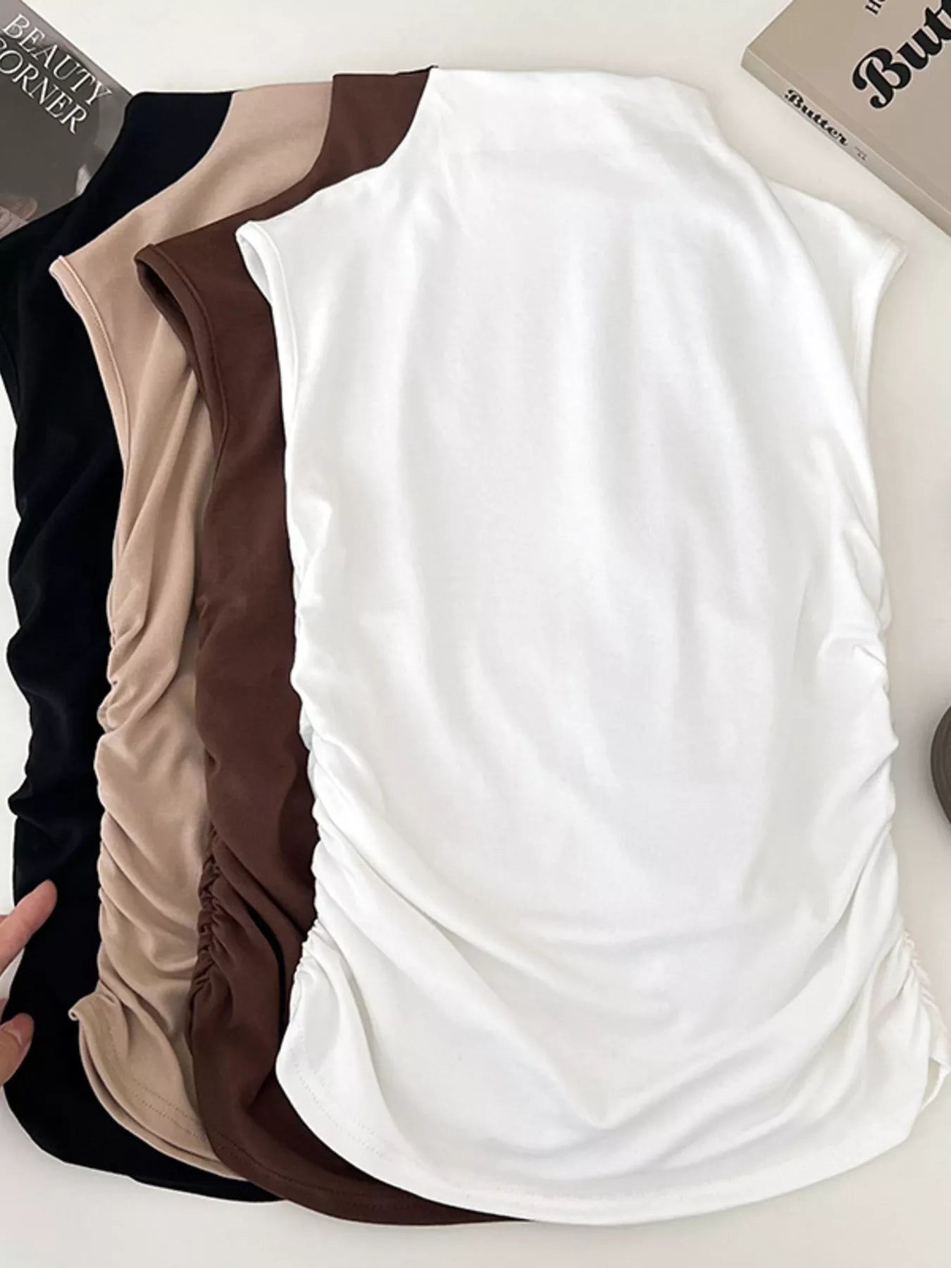 Three tank tops in black, beige, and white on a white background