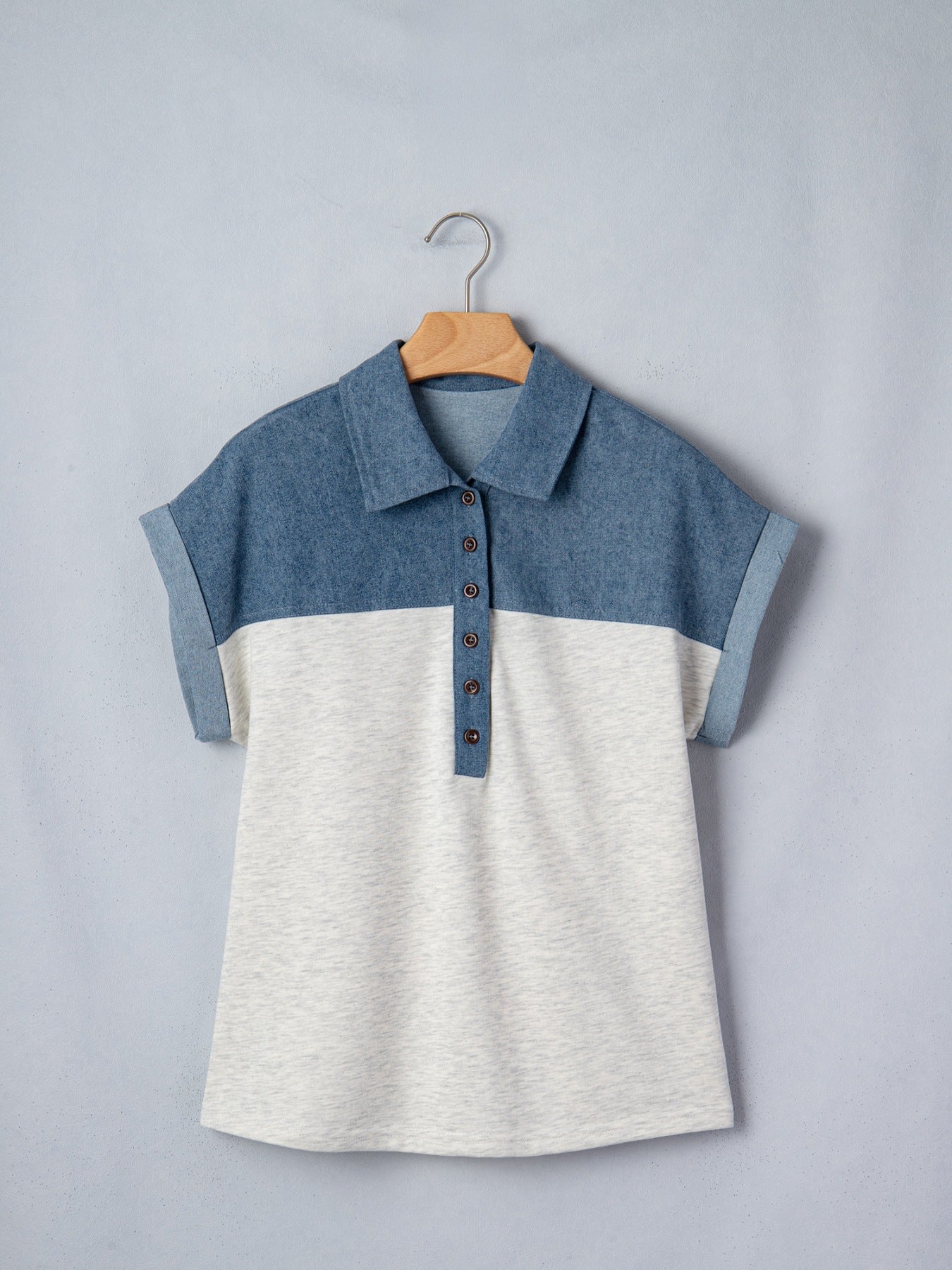 Two-tone blue and white shirt on a hanger against a gray background