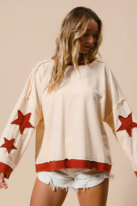 Woman wearing a white top with red star designs on a beige background