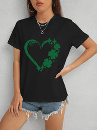 Person wearing a black t-shirt with a green shamrock heart design on a gray background