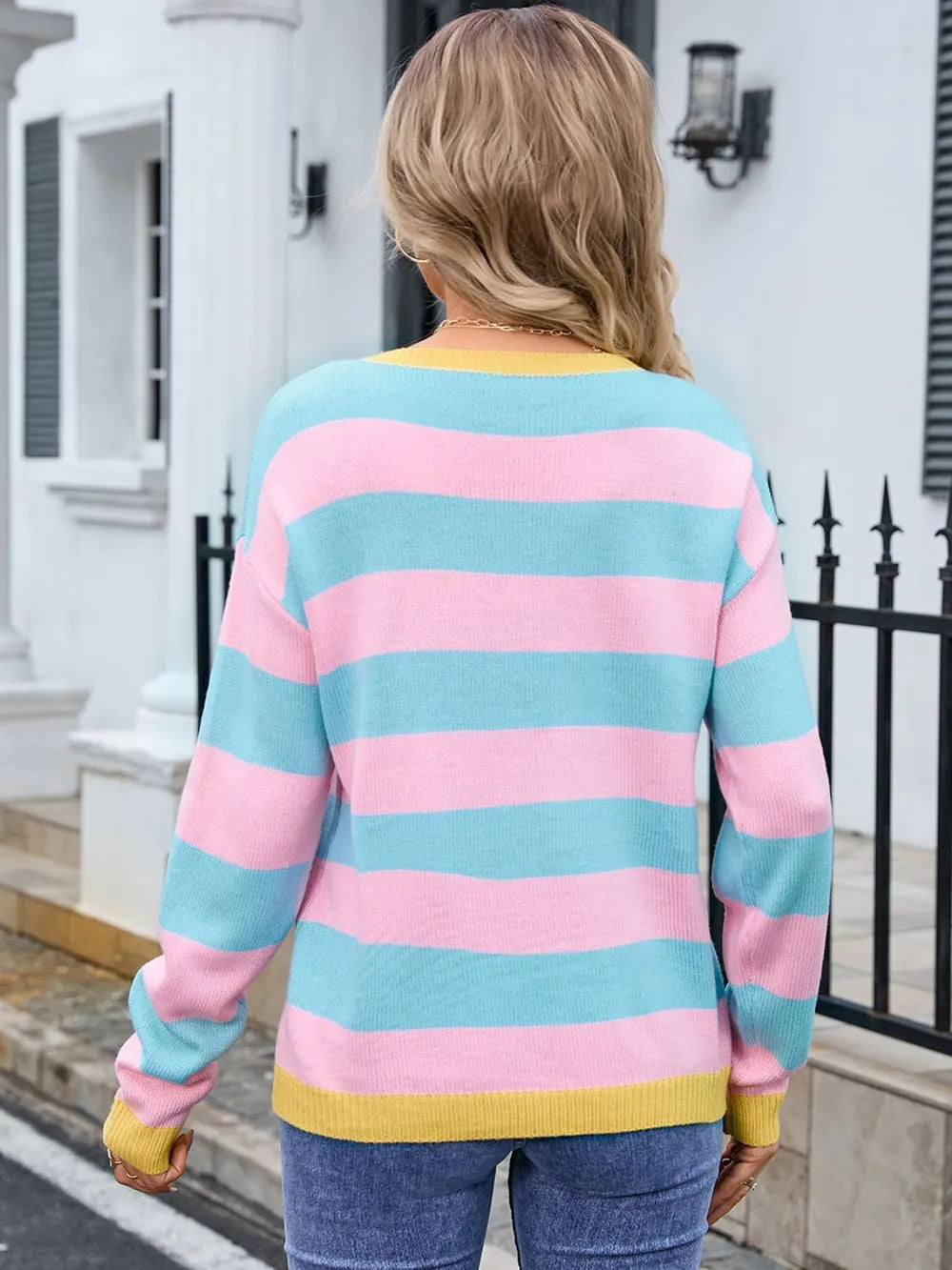 Person wearing a colorful striped sweater in front of a building.