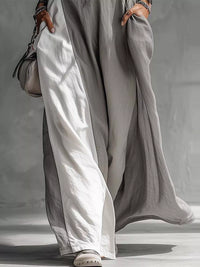 Person wearing a long, light gray dress with wide-leg pants against a neutral background