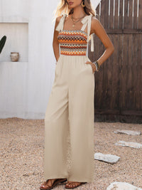 Woman wearing a colorful top and beige jumpsuit standing outdoors.