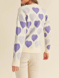 Person wearing a sweater with purple heart patterns on a beige background