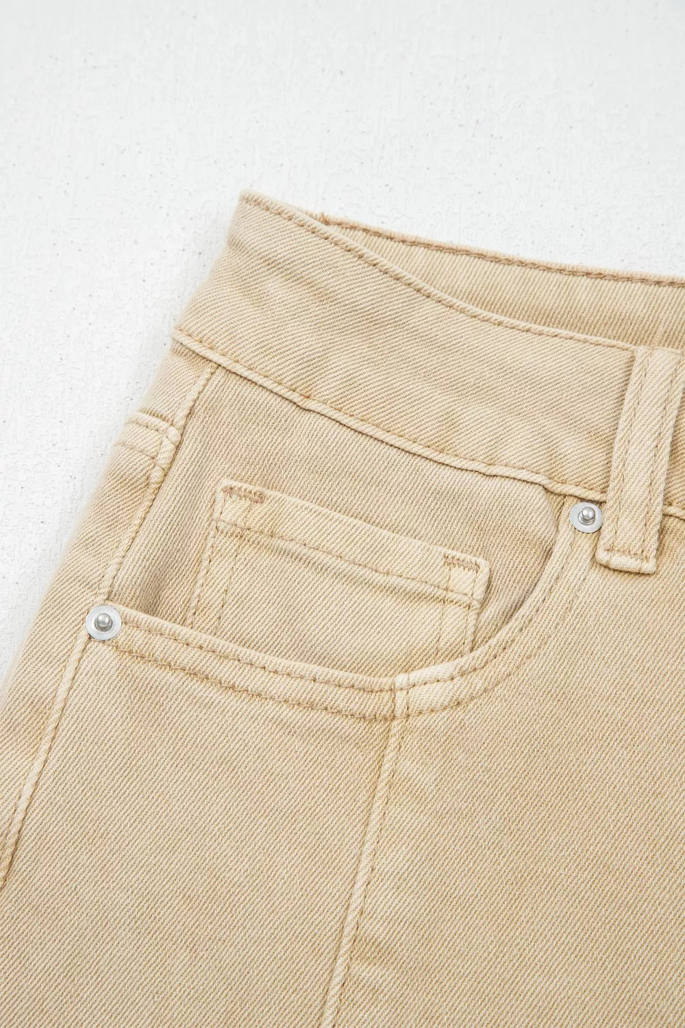 Close-up of beige pants with a pocket on a light gray background