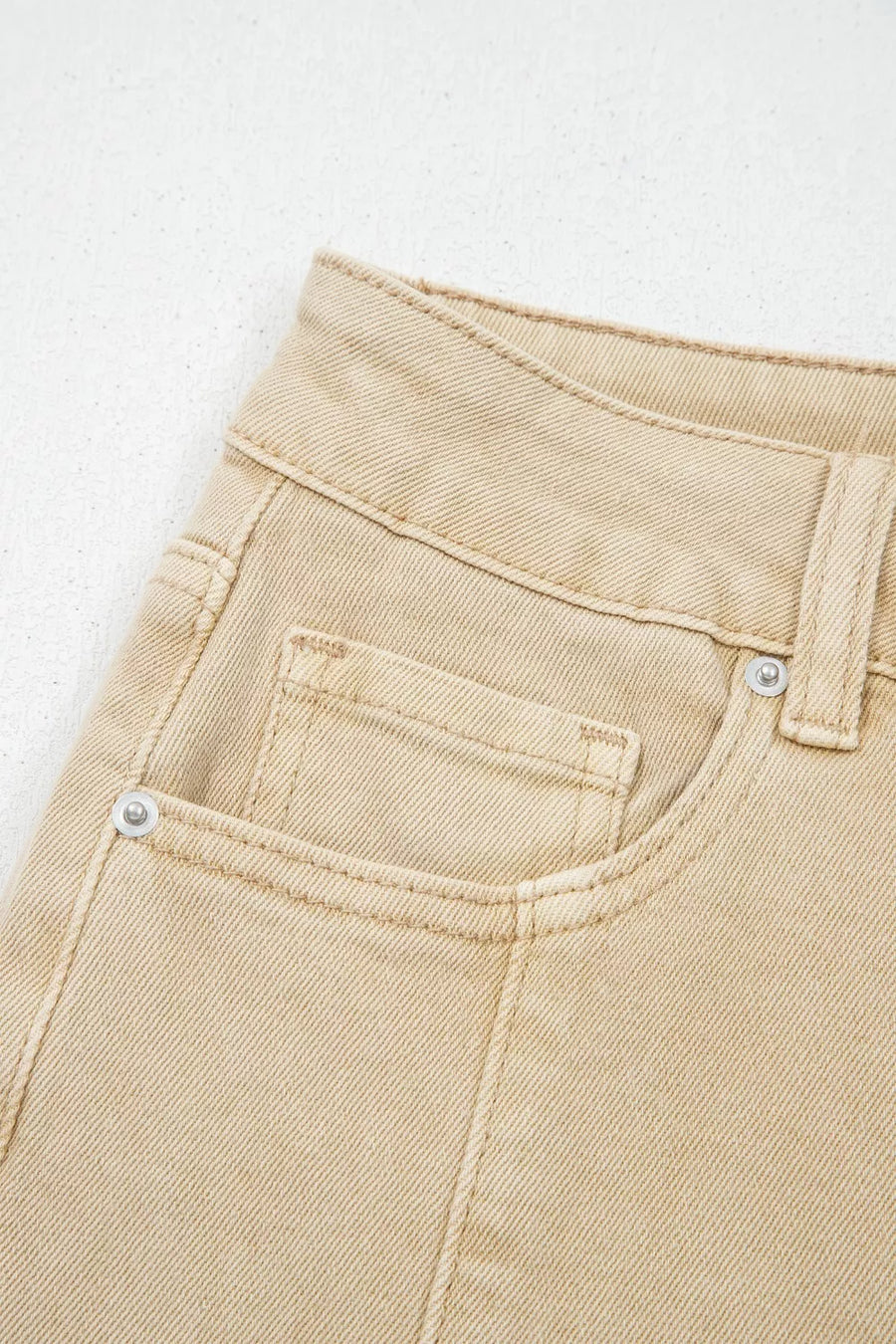 Close-up of beige pants with a pocket on a light gray background