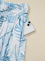 Blue leaf-patterned skirt with a white phone on a beige background