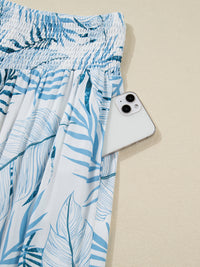 Blue leaf-patterned skirt with a white phone on a beige background