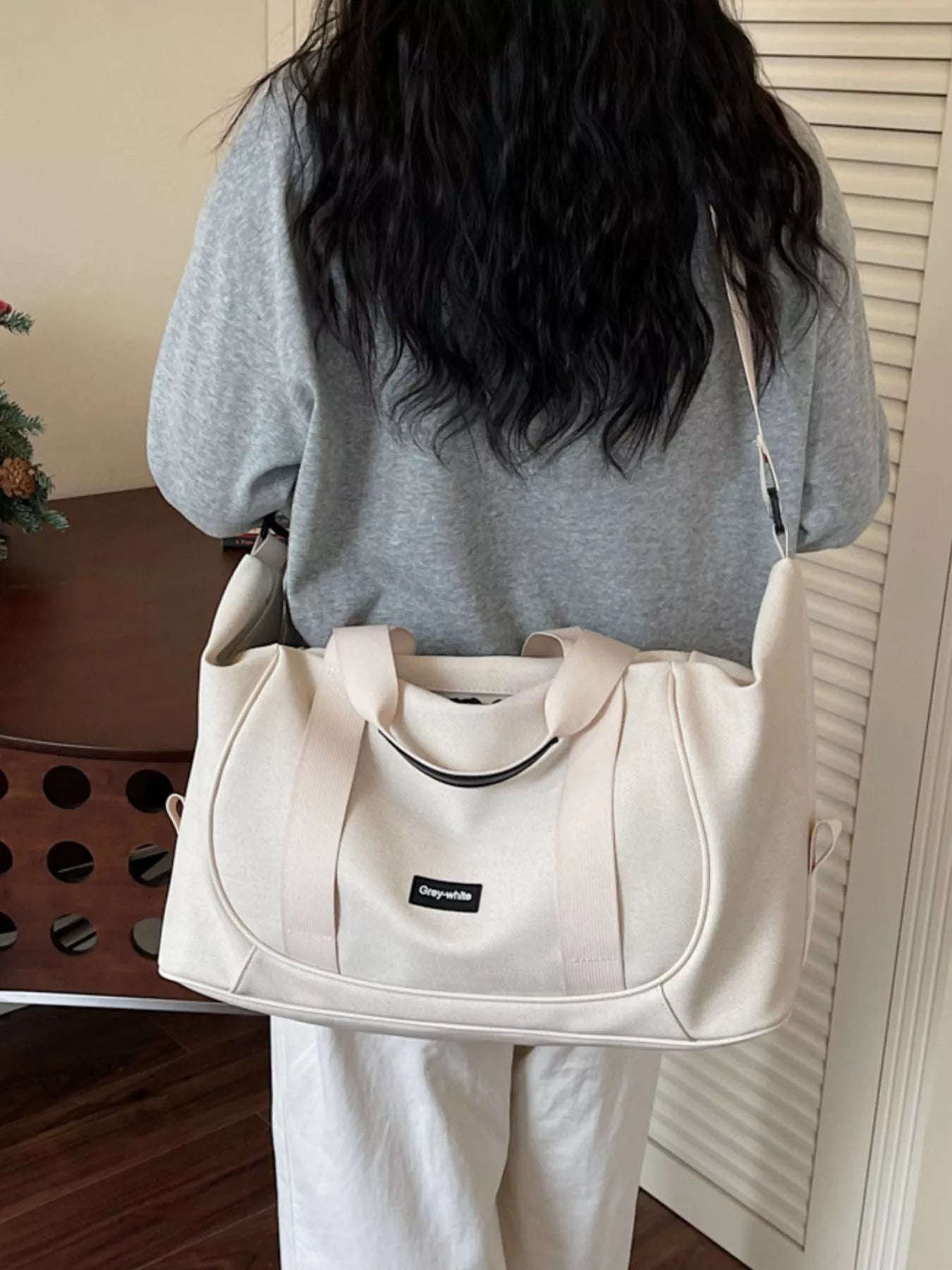 Person holding a beige bag with a visible brand logo indoors.