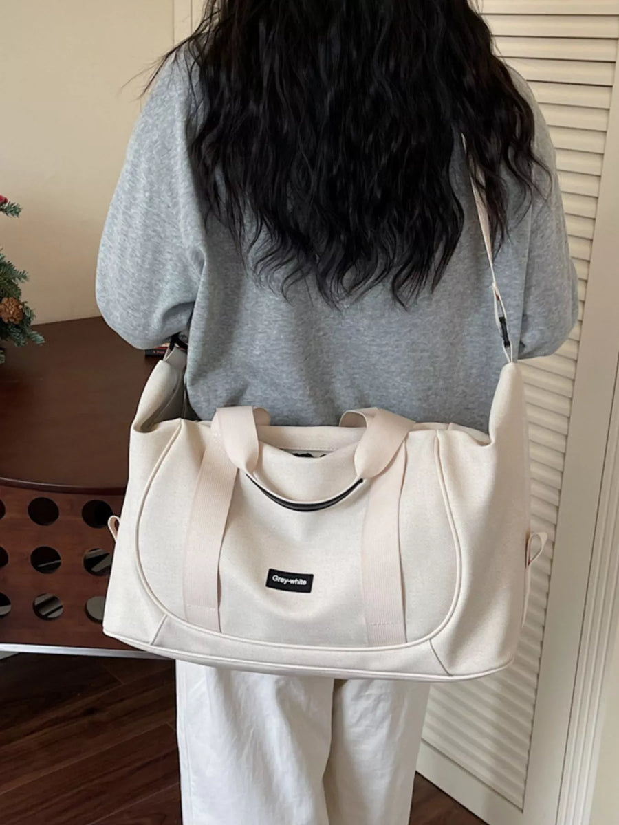 Person holding a beige bag with a visible brand logo indoors.