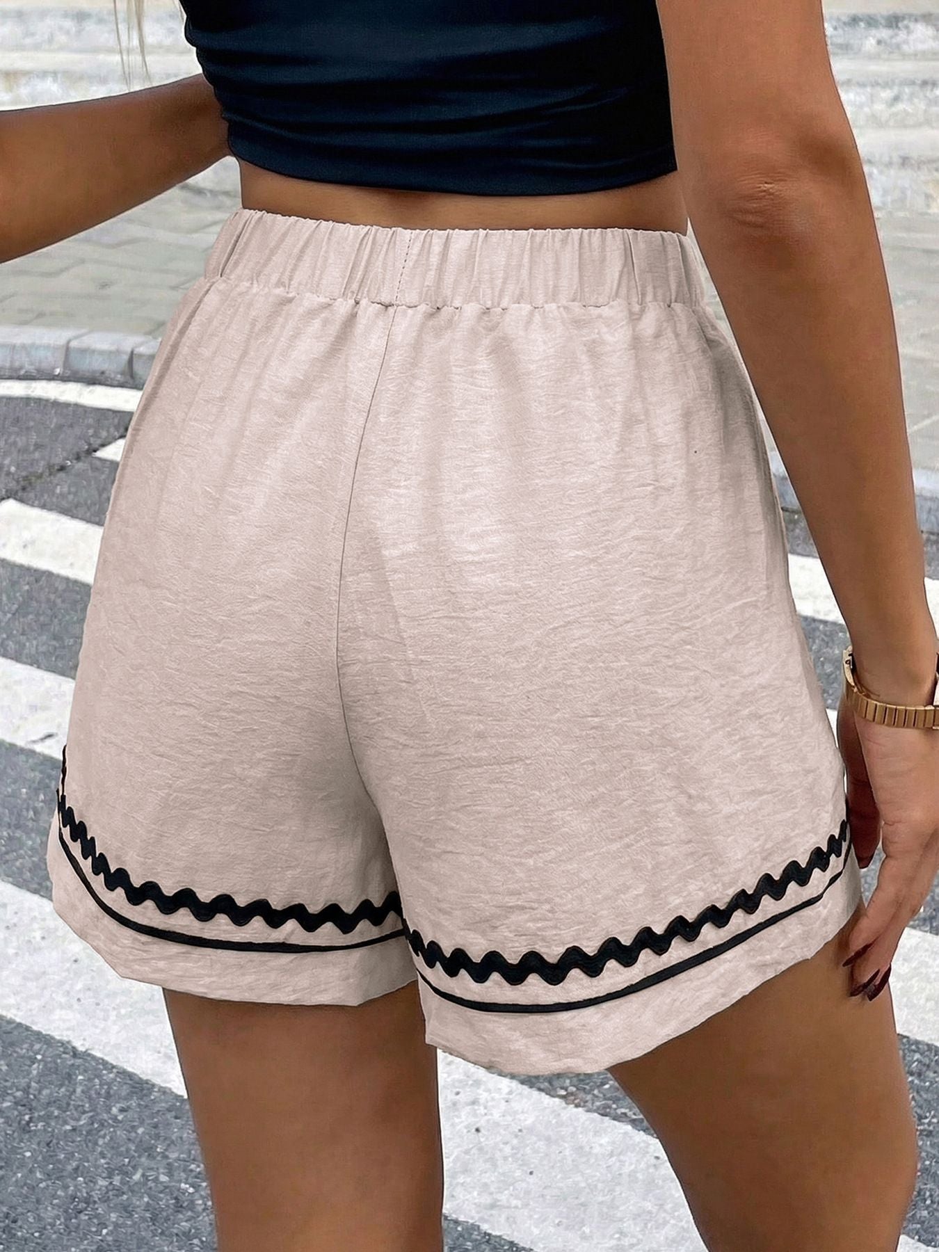 Beige shorts with black trim worn by a person on a street.