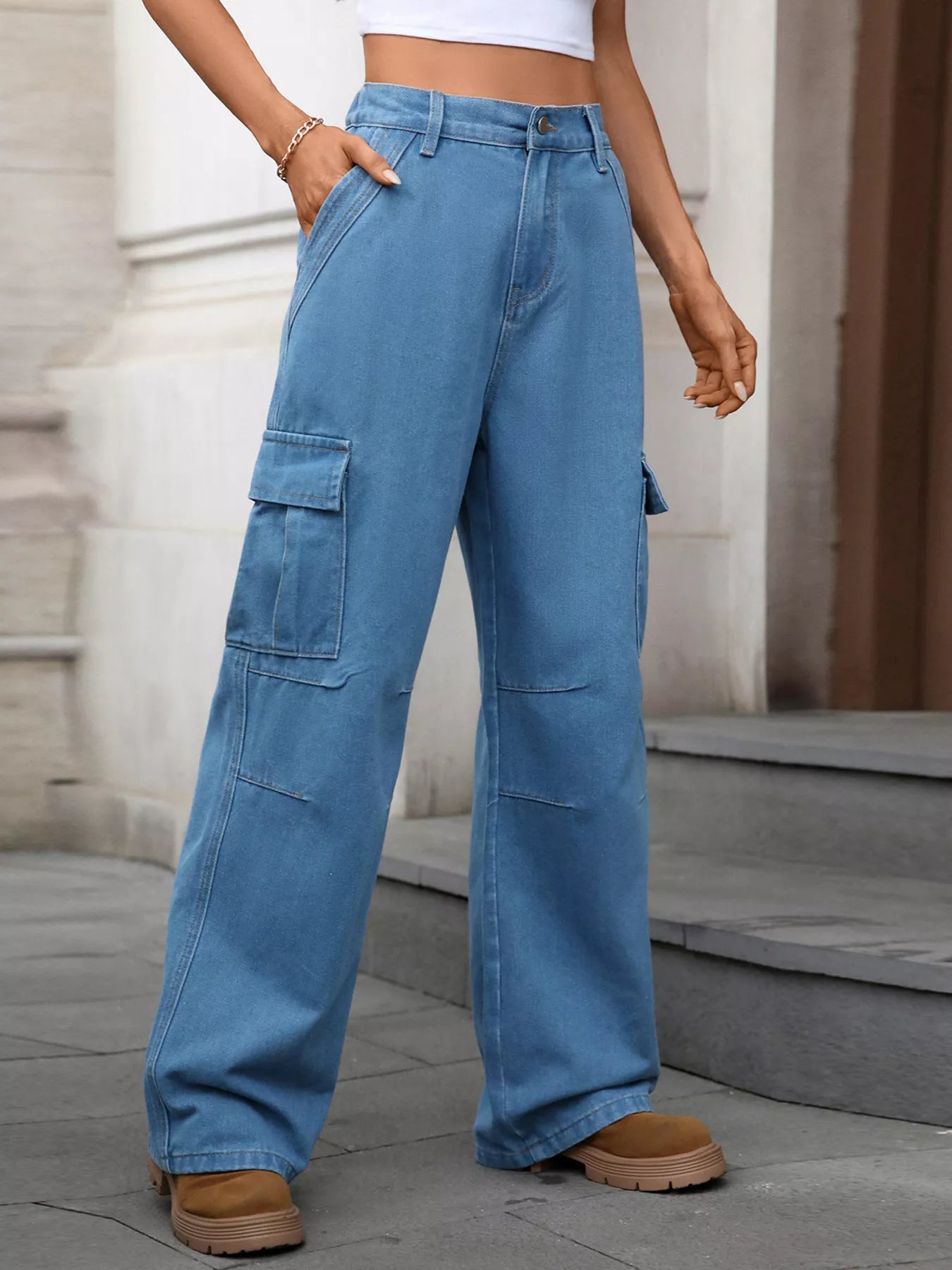Person wearing blue cargo pants standing on a stone pavement.