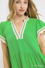 Woman wearing a green dress with white and green trim on a white background