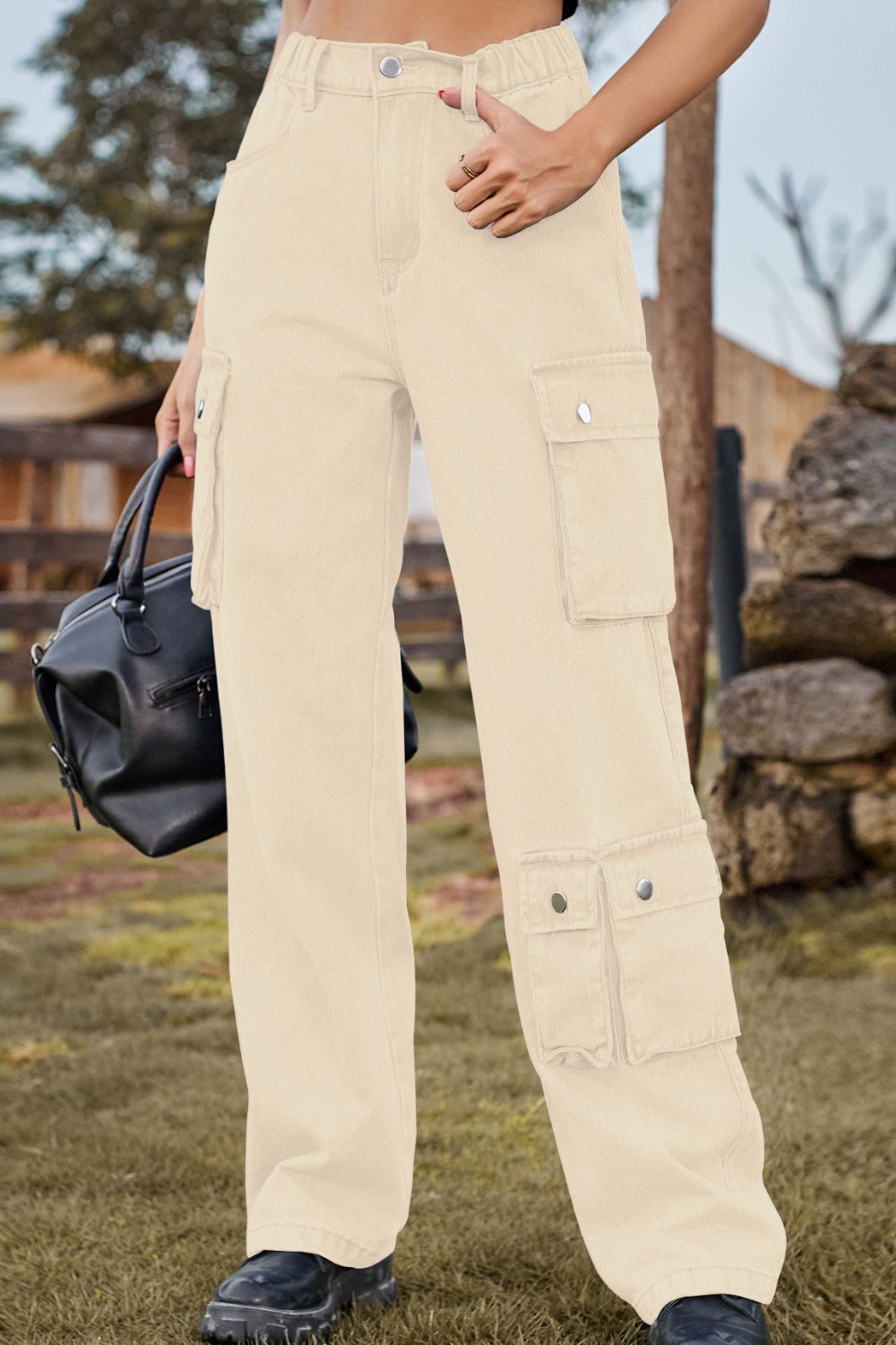 Person wearing beige cargo pants holding a black bag outdoors.