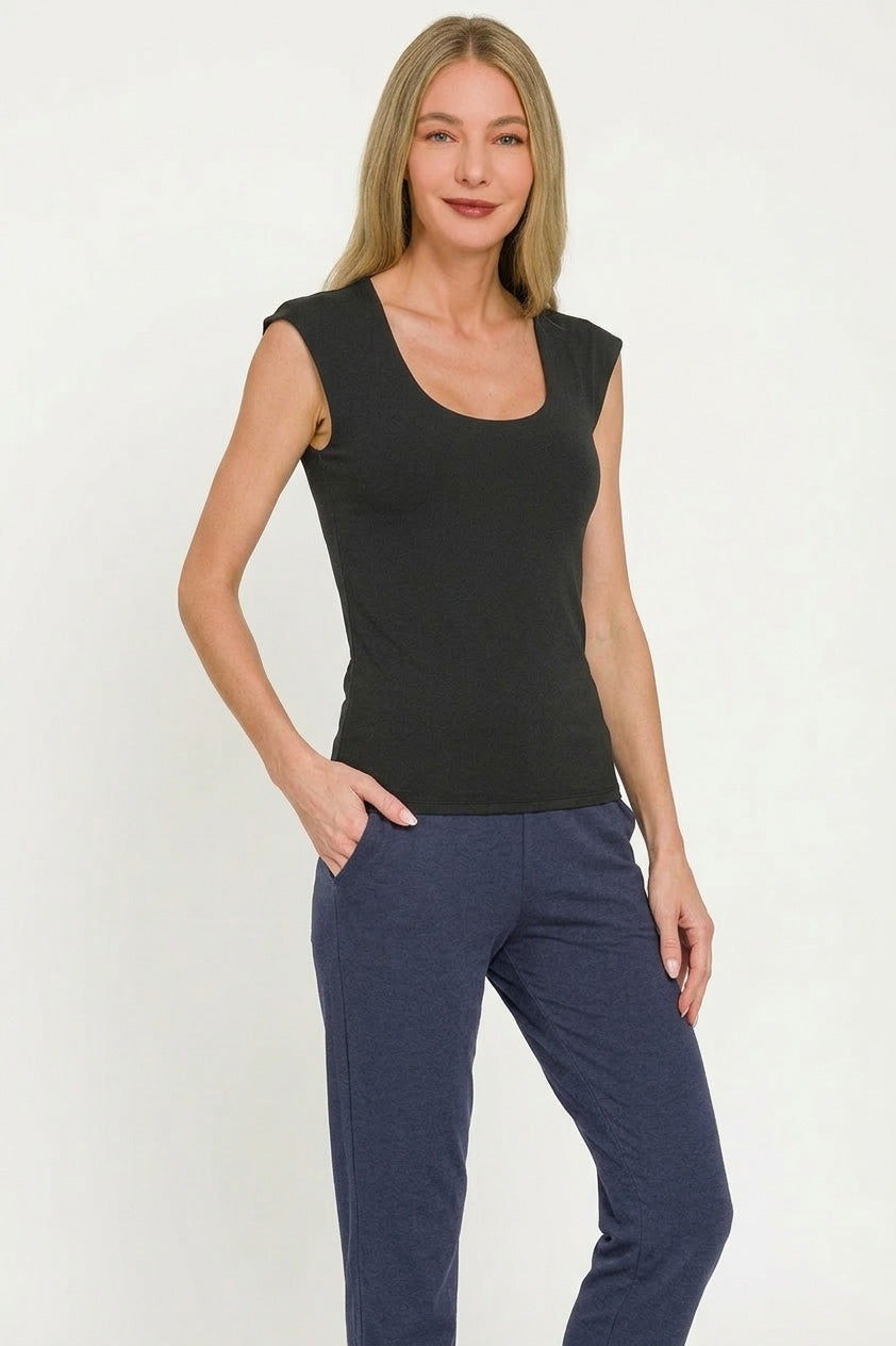 Woman wearing a black sleeveless top and blue pants on a white background