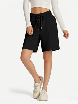 Person wearing black shorts with a drawstring on a white background